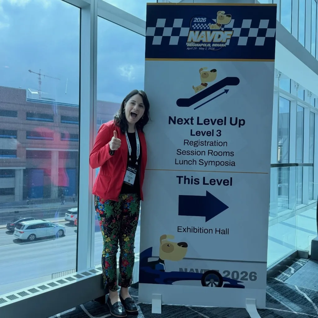 Dr. Gaby giving a thumbs up in front of a NAVDF 2026 directional sign at the Indianapolis Convention Center