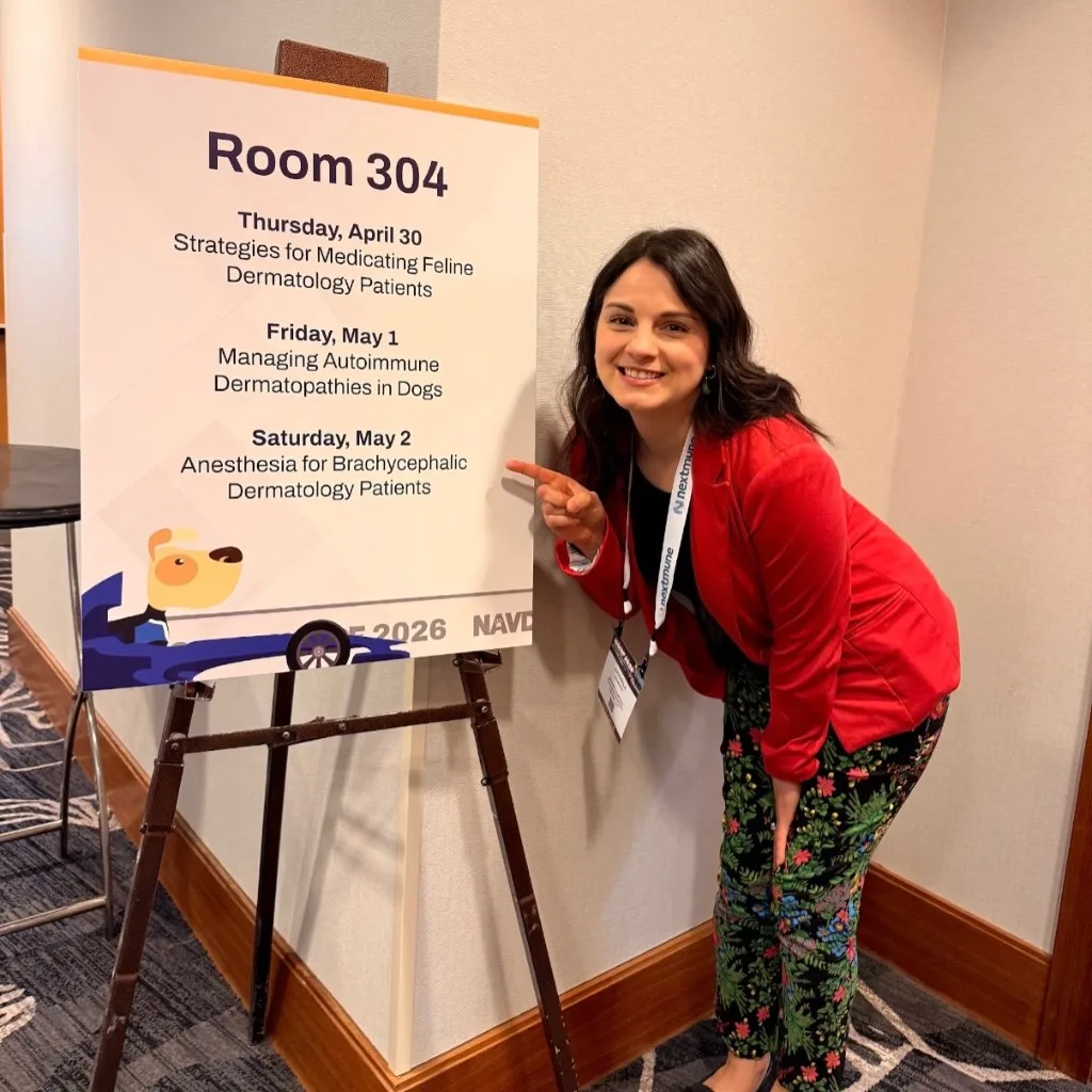 Dr. Gaby pointing at the Room 304 lecture schedule listing her three NAVDF talks